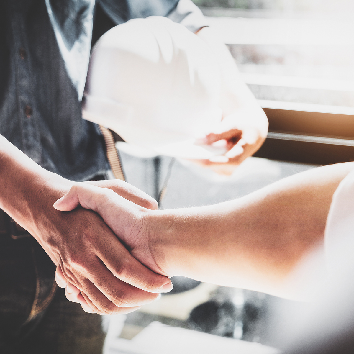 shaking hands, one person holding a hardhat